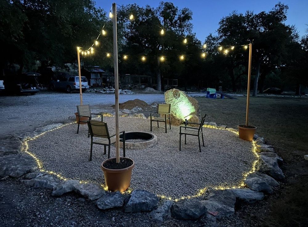 After - finished outdoor fire pit with gravel, seating, string lights and landscaping