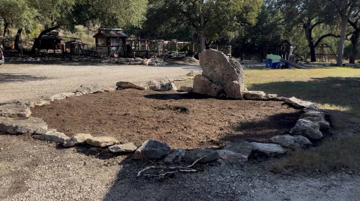 Before - bare dirt circle with rock border for outdoor fire pit area